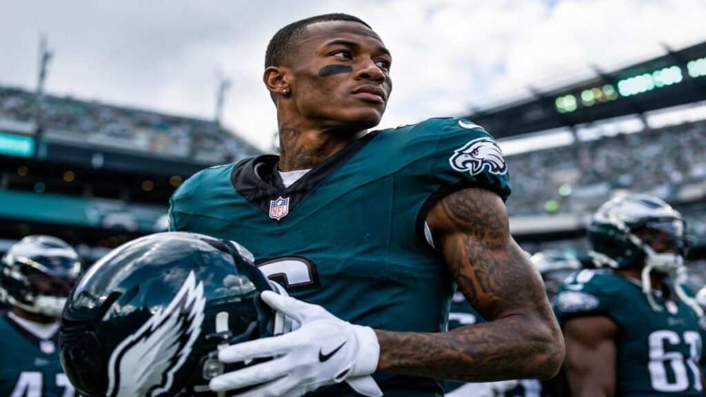 DeVonta Smith Philadelphia Eagles wide receiver leaping to catch a football in a dynamic action pose during a sunny practice or game, wearing number 6 green jersey, focused intensity, stadium background.