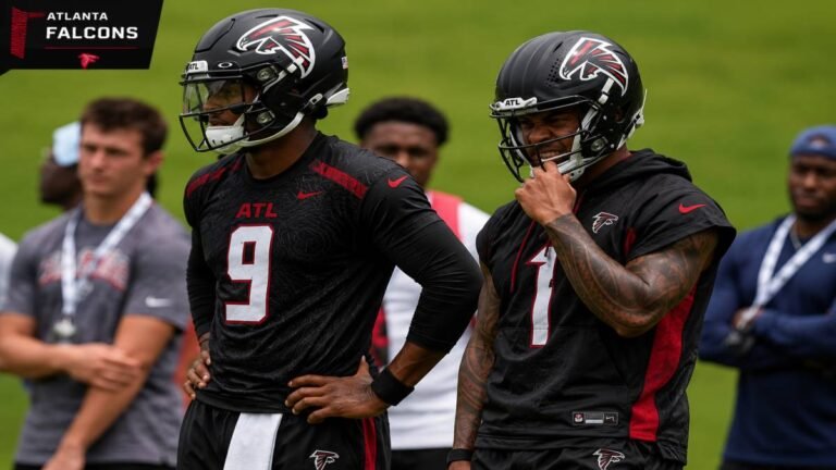 Atlanta Falcons quarterback in red jersey throws during OTAs 7-on-7 drills at Flowery Branch while another quarterback observes, capturing the ongoing Michael Penix Jr. recovery and Tua Tagovailoa reps split in the 2026 QB competition.