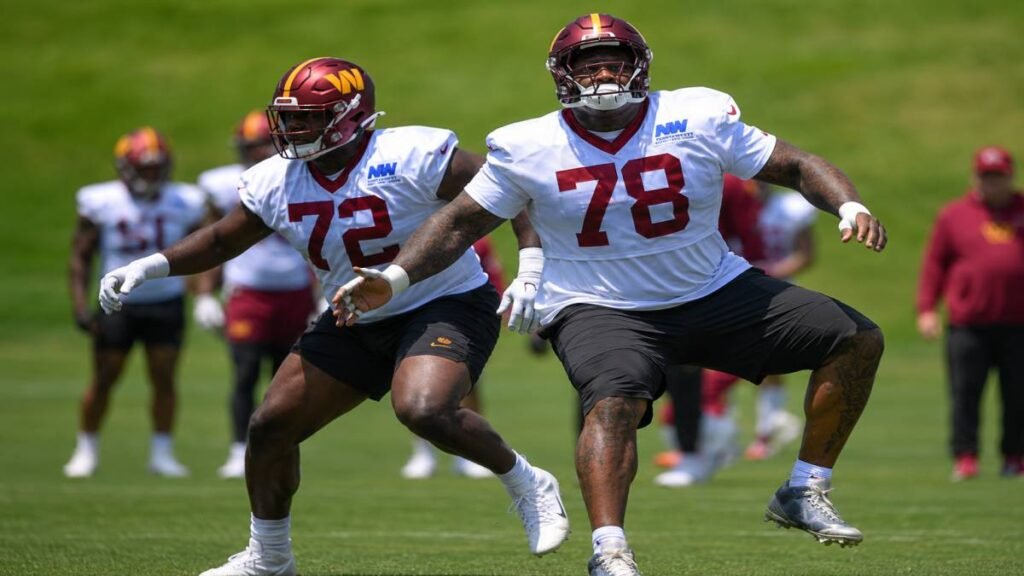 Washington Commanders offensive tackles Laremy Tunsil and Josh Conerly Jr. share an intense training moment on a sunlit Alabama football field, with Tunsil offering technique guidance during their dedicated offseason routine.