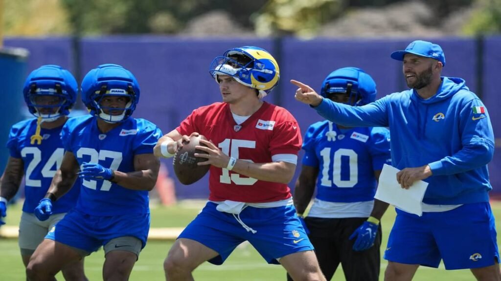 Los Angeles Rams rookie quarterback Ty Simpson listens closely as 2025 NFL MVP Matthew Stafford breaks down plays during an offseason film session in a modern team meeting room.